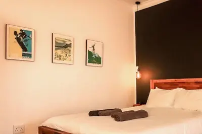 a bedroom with two beds and pictures on the wall at Surfhostel Cape Town in Cape Town