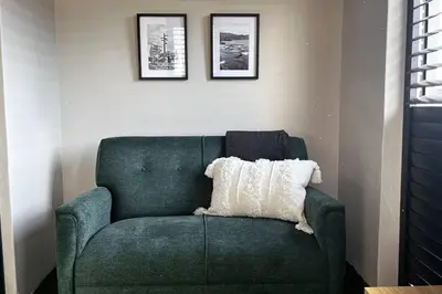 a green chair with a white pillow in a room at Hermanus Waterfront Apartment No.20 in Hermanus
