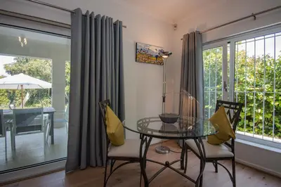 a dining room with a glass table and chairs at Garden- Pool flat with Solar Electricity in Somerset West