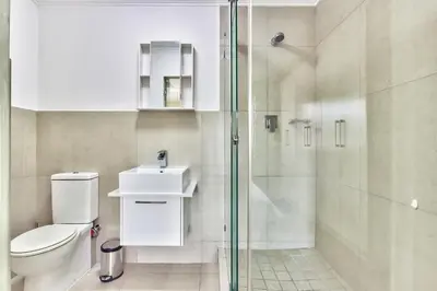 a bathroom with a toilet and a glass shower at 2 Bedroom Apartment in Century City 204QS in Cape Town