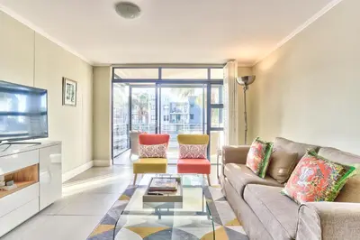 a living room with a couch and chairs and a tv at 2 Bedroom Apartment in Century City 204QS in Cape Town