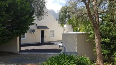 a white house with a tree in front of it at Mountain View Self-Catering Apartments in Somerset West