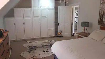 a bedroom with a white bed and white cabinets at Mountain View Self-Catering Apartments in Somerset West