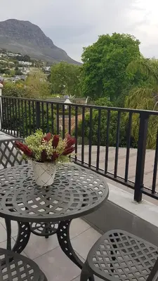 a table with a vase of flowers on a balcony at Mountain View Self-Catering Apartments in Somerset West