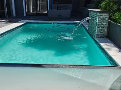 a swimming pool with a water fountain at Willow Retreat Blouberg in Cape Town
