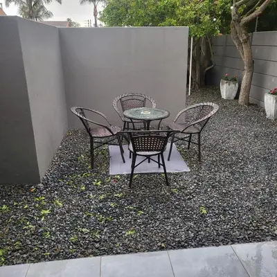 a table and chairs sitting on top of gravel at Willow Retreat Blouberg in Cape Town