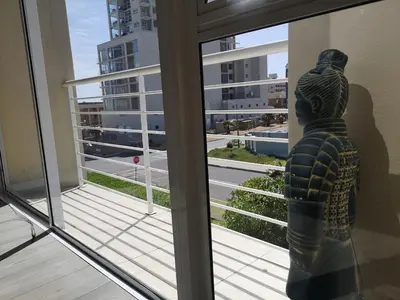 a statue looking out a window at a view of a city at Blouberg Beach Luxury Apartment in Cape Town