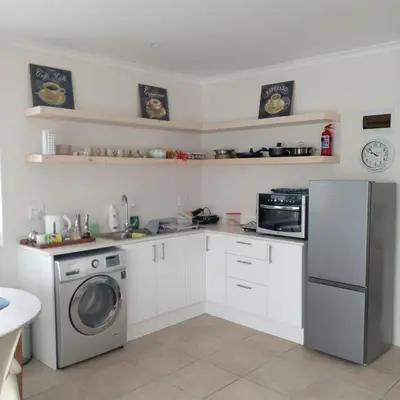 a kitchen with white cabinets and a washer and dryer at Bing Heights Suite in Hermanus