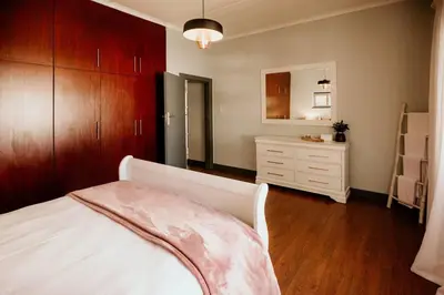 a bedroom with a white bed and a dresser at Villa Visser in Cape Town