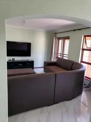 a living room with a brown couch and a flat screen tv at Capetown Adilo Villa in Cape Town