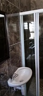 a bathroom with a sink and a shower at El-Gibor Best Guest House in Cape Town