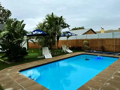 a swimming pool with two lawn chairs and umbrellas at El-Gibor Best Guest House in Cape Town