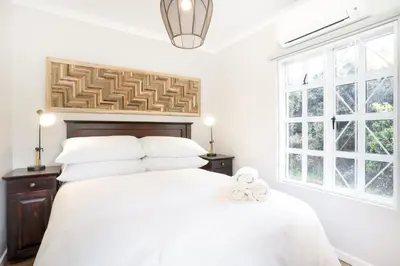 a white bedroom with a large bed and two windows at Avemore Winelands Home - wood fired hottub and full power back up in Stellenbosch