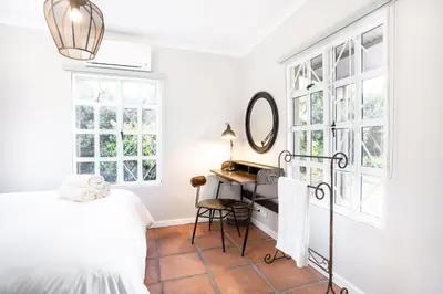 a bedroom with a bed and a desk with a mirror at Avemore Winelands Home - wood fired hottub and full power back up in Stellenbosch