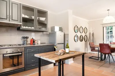 a kitchen with black cabinets and a wooden table at Avemore Winelands Home - wood fired hottub and full power back up in Stellenbosch