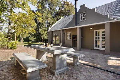 a picnic table and benches in front of a house at Avemore Winelands Home - wood fired hottub and full power back up in Stellenbosch