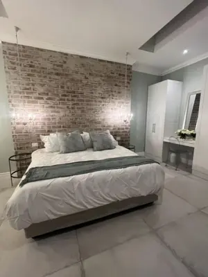 a bedroom with a large bed with a brick wall at Two on Milner - OAK TREE COTTAGE - Stylish open-plan Guesthouse in Rondebosch in Cape Town