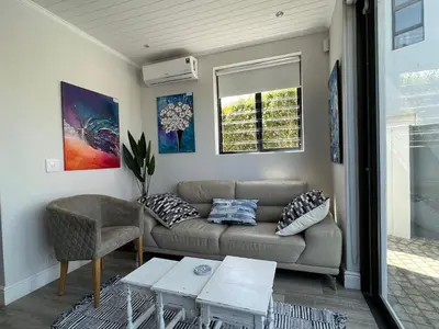 a living room with a couch and a table at Cowrie Cottage Self Catering in Cape Town