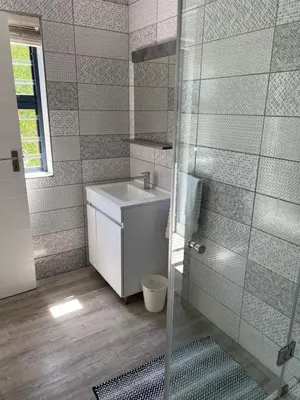 a bathroom with a sink and a shower at Cowrie Cottage Self Catering in Cape Town