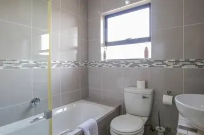 a bathroom with a tub and a toilet and a sink at Howard Davis 28B by CTHA in Cape Town