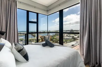 a bedroom with a bed and a large window at Burmeister 607 - Top Floor Corner 2 Bedroom Apartment with Sea and Lagoon Views - Onsite Parking in Cape Town