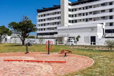 two playgrounds in a park in front of a building at Burmeister 607 - Top Floor Corner 2 Bedroom Apartment with Sea and Lagoon Views - Onsite Parking in Cape Town