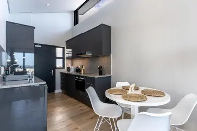 a kitchen with a white table and white chairs at Burmeister 607 - Top Floor Corner 2 Bedroom Apartment with Sea and Lagoon Views - Onsite Parking in Cape Town