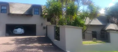 a white house with a gate and palm trees at Traduire in Cape Town