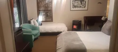 a hotel room with two beds and a chair and a piano at Traduire in Cape Town