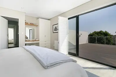 a bedroom with a large bed and a balcony at On the Greens Villa in Cape Town