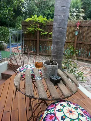 a table and chairs with a glass of wine on a deck at Lucano 1 Stellenbosch in Stellenbosch