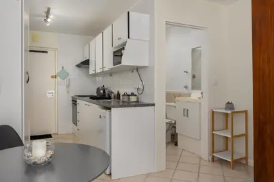 a kitchen with white cabinets and a table at Ocean View B201B in Cape Town