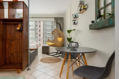 a table and chairs in a room with a window at Ocean View B201B in Cape Town