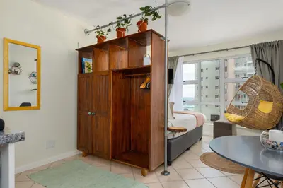 a room with a bed and a wooden cabinet at Ocean View B201B in Cape Town