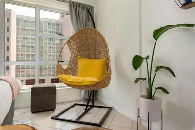 a wicker chair in a room with a window at Ocean View B201B in Cape Town