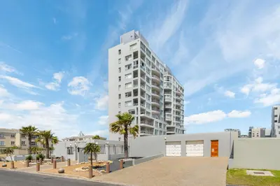 a tall white building with palm trees in front of it at Ocean View B201B in Cape Town