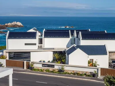 a white house with the ocean in the background at Boutique Ocean Views - incorporating Wendy's in Hermanus