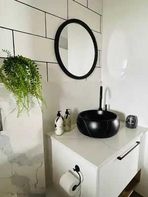 a bathroom with a black sink and a mirror at Luxurious 2-bedroom beach apartment with a view! in Bloubergstrand