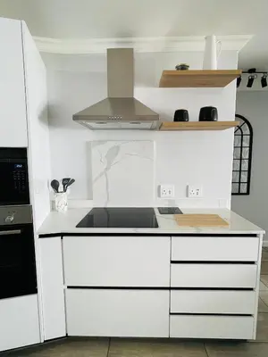 a kitchen with white cabinets and a stove top oven at Luxurious 2-bedroom beach apartment with a view! in Bloubergstrand