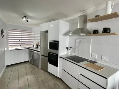 a kitchen with white cabinets and a counter top at Luxurious 2-bedroom beach apartment with a view! in Bloubergstrand