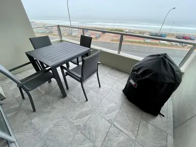 a table and chairs and a bag on a balcony at Luxurious 2-bedroom beach apartment with a view! in Bloubergstrand
