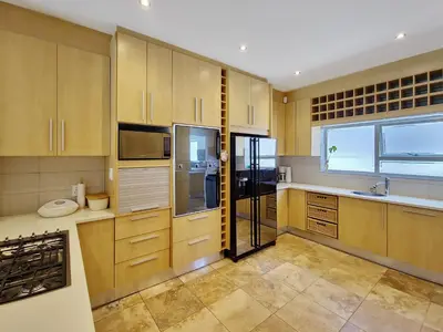 a large kitchen with wooden cabinets and a window at Kite, Wind, Waves Beach Villa in Cape Town