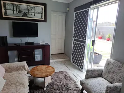 a living room with a couch and a table and a tv at 68 On Hofmeyr in Strand