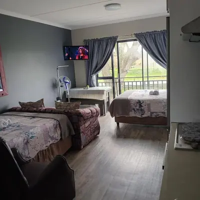 a bedroom with two beds and a tv on the wall at Cederberg Estate in Cape Town