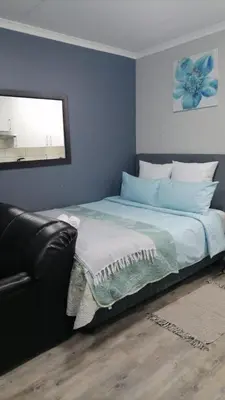 a bedroom with a bed with a couch and a window at Cederberg Estate in Cape Town
