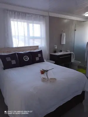 a bedroom with a large white bed and a sink at Stay Palm 1 in Cape Town