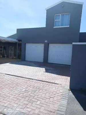 a house with two garage doors and a brick driveway at Stay Palm 1 in Cape Town