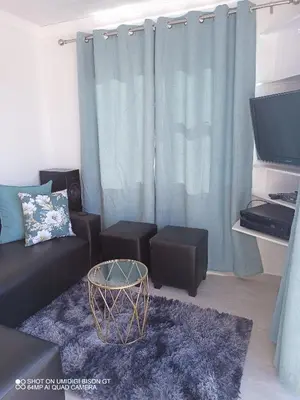 a living room with a black couch and a tv at Stay Palm 1 in Cape Town