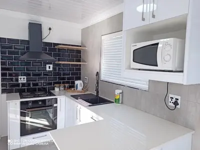 a kitchen with white cabinets and a microwave at Stay Palm 1 in Cape Town