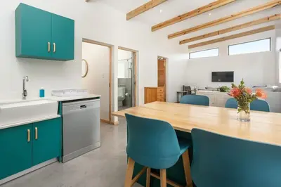 a kitchen with a wooden table and blue chairs at Mountain and Sea Cottage in Hermanus